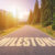 Asphalt road with arrow guideline and Milestone letters painted on the surface. An image of a road milestones are representative of success in the future goal. Road to success with light of the sun